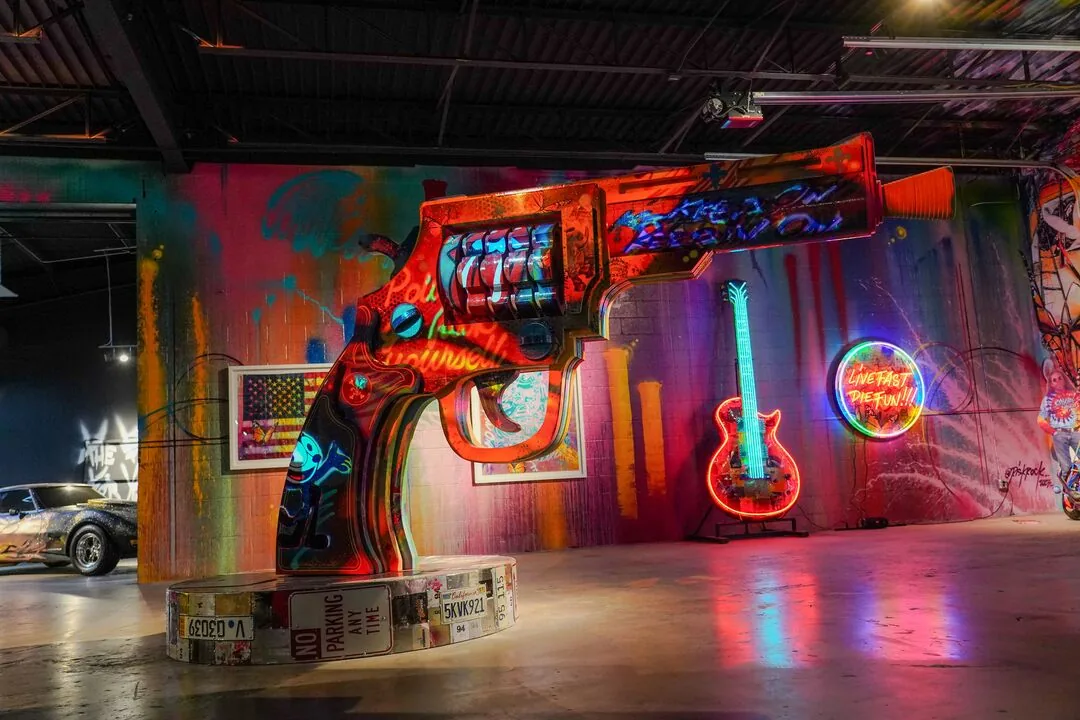 Inside Gallery DeFi: a painted revolver sculpture, a neon guitar and a vintage car among the murals